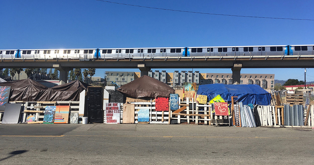 Figure 3. The view passing by the encampment on Fifth Street. BART (Bay Area Rapid Transit) can be seen and heard hurdling by, routinely interrupting conversations and sleep, Oakland, California, 2021. Photograph by Ben Jameson-Ellsmore.